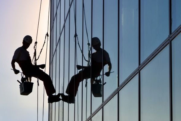 A man cleans building windows to enhance its appearance and clarity.
